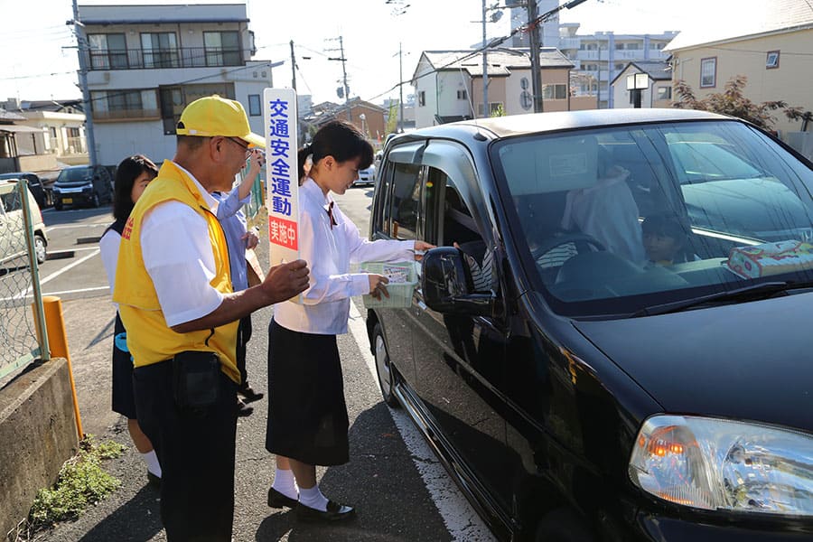 ▲高田高校生と啓発品を配布して交通安全を呼びかけ